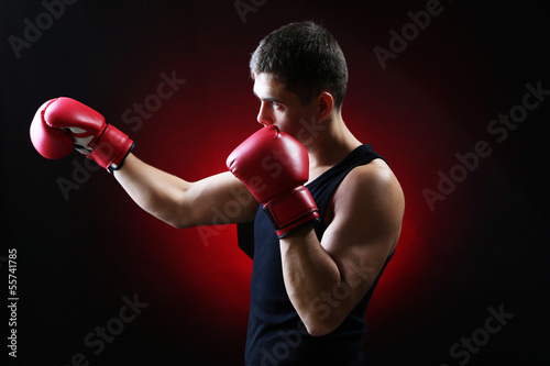 Handsome young muscular boxer on dark background