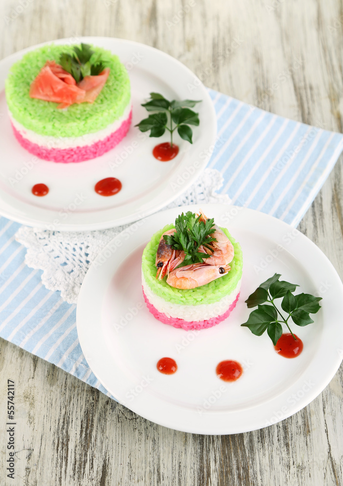 Colored rice on plates on napkin on wooden table Colored rice on plates on napkin on wooden table