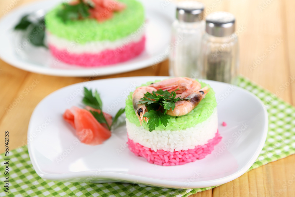 Colored rice on plates on napkin on wooden table Colored rice on plates on napkin on wooden table