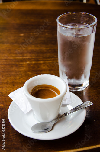 White espresso cup with glass of cold water on the wooden table