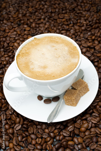 cup of cappuccino with brown sugar on coffee beans