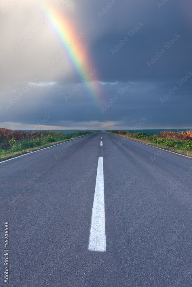 Driving om empty road under the rainbow