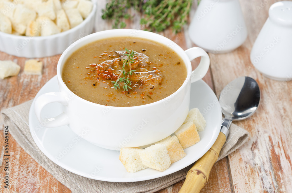 Mushroom cream soup with croutons and thyme in a white bowl Mushroom cream soup with croutons and thyme in a white bowl