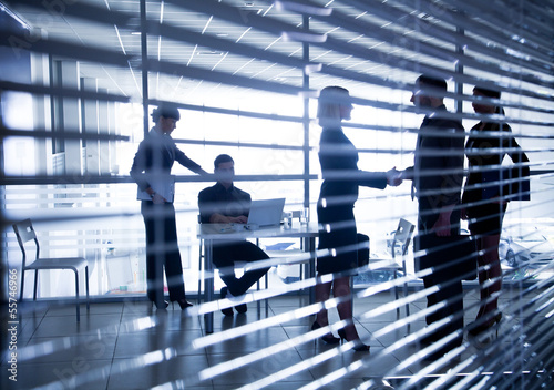 silhouettes of business people through the blinds