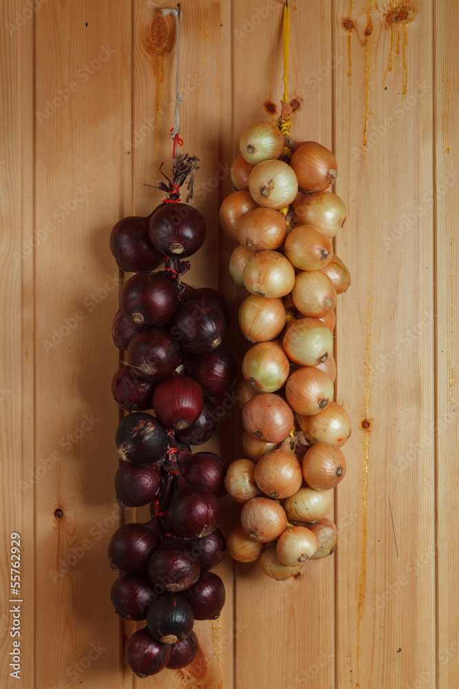 hanging strings of red and white onions on wooden wall hanging strings of red and white onions on wooden wall