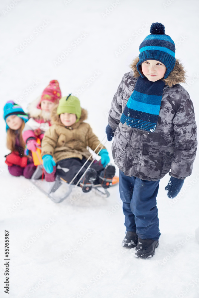 Boy pulls sledges with younger children, focus on boy Boy pulls sledges with younger children, focus on boy