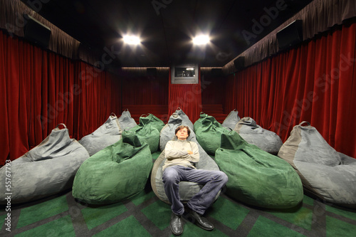 Man watches movie in comfortable seat in small cinema theater. photo