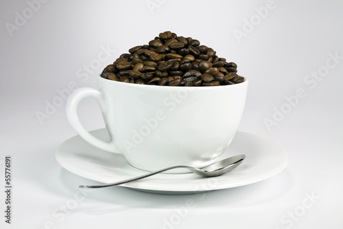White ceramic cup with roasted coffee seeds.