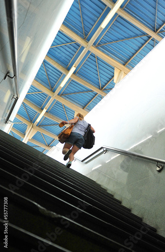 Mujer joven cargada de bolsos de viaje en la escalera