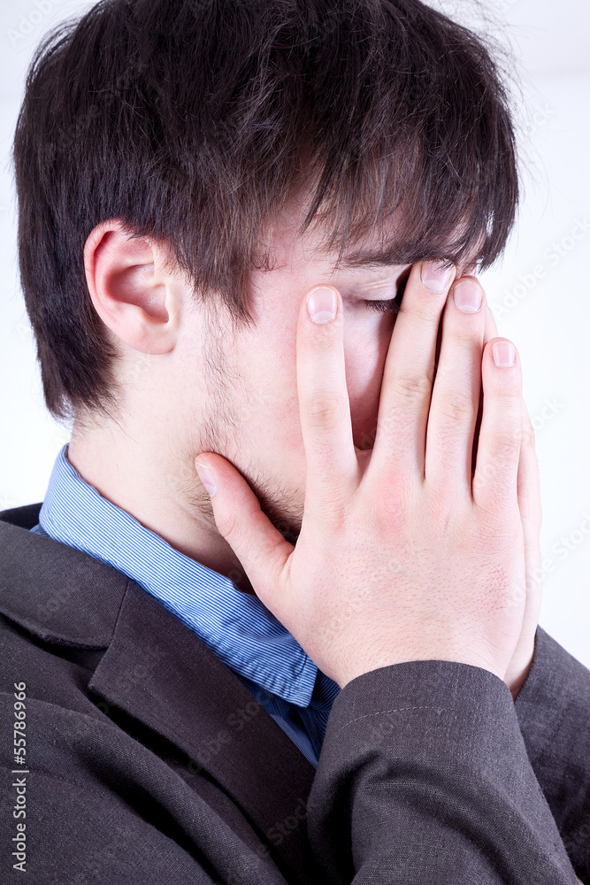 Young man holding his hands over his face Young man holding his hands over his face