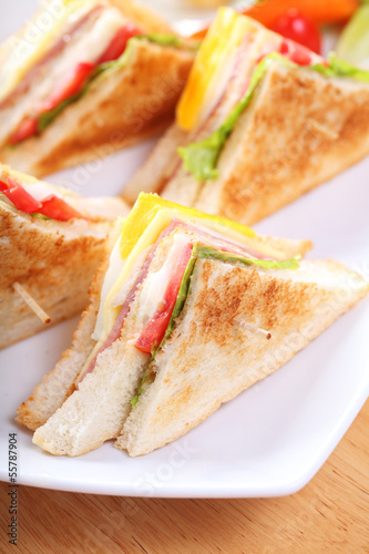 Sandwich with bacon and vegetables on white dish
