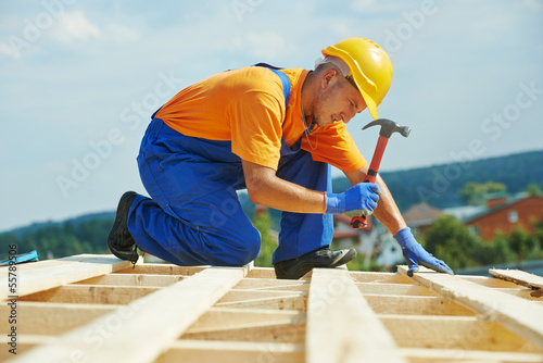 Roofer carpenter works on roof photo