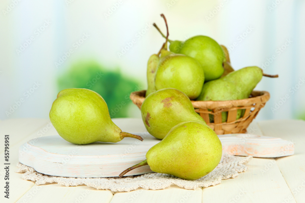Pears on wooden cutting board, on light background