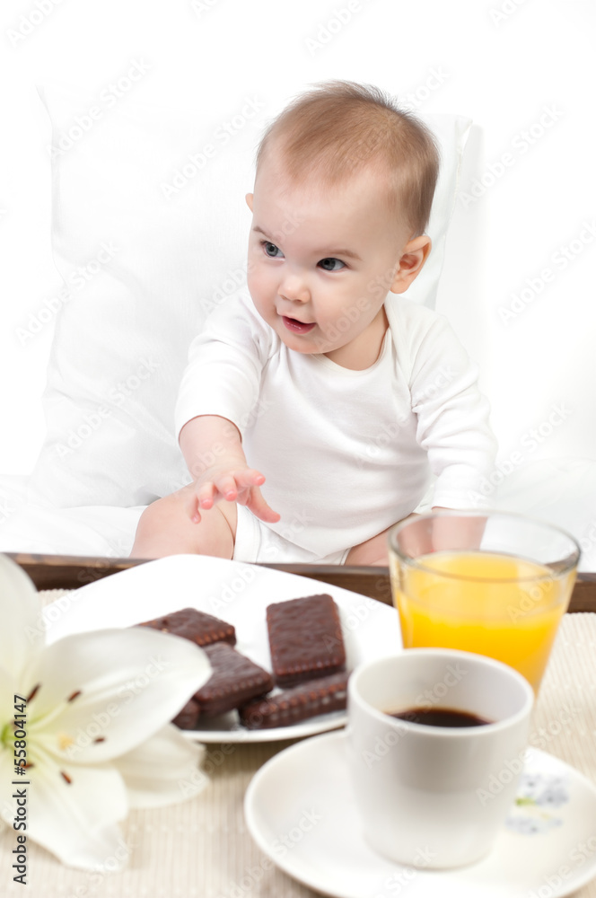 Cute baby examines a wooden tray with a breakfast Cute baby examines a wooden tray with a breakfast