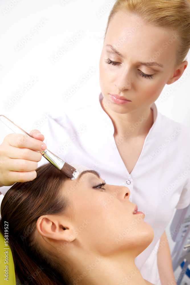 young woman getting beauty skin mask treatment on her face with young woman getting beauty skin mask treatment on her face with