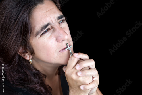 Hispanic woman praying and kissing a crucifix