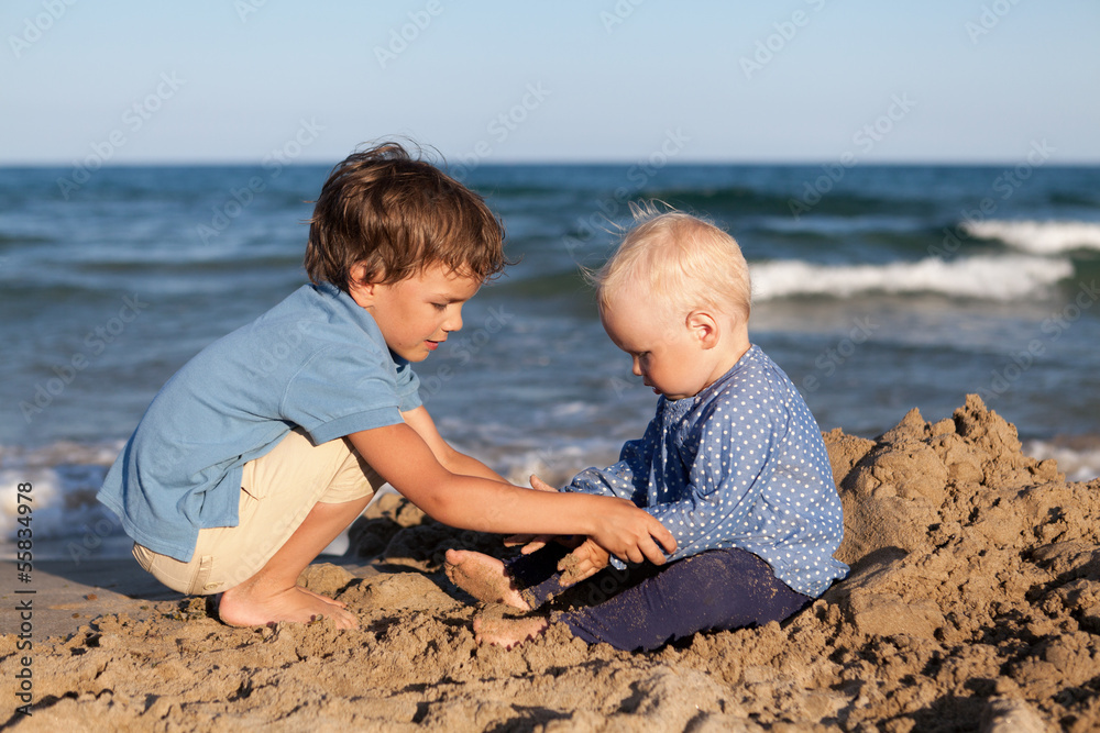 Brother and sister playing in sand at beach Brother and sister playing in sand at beach