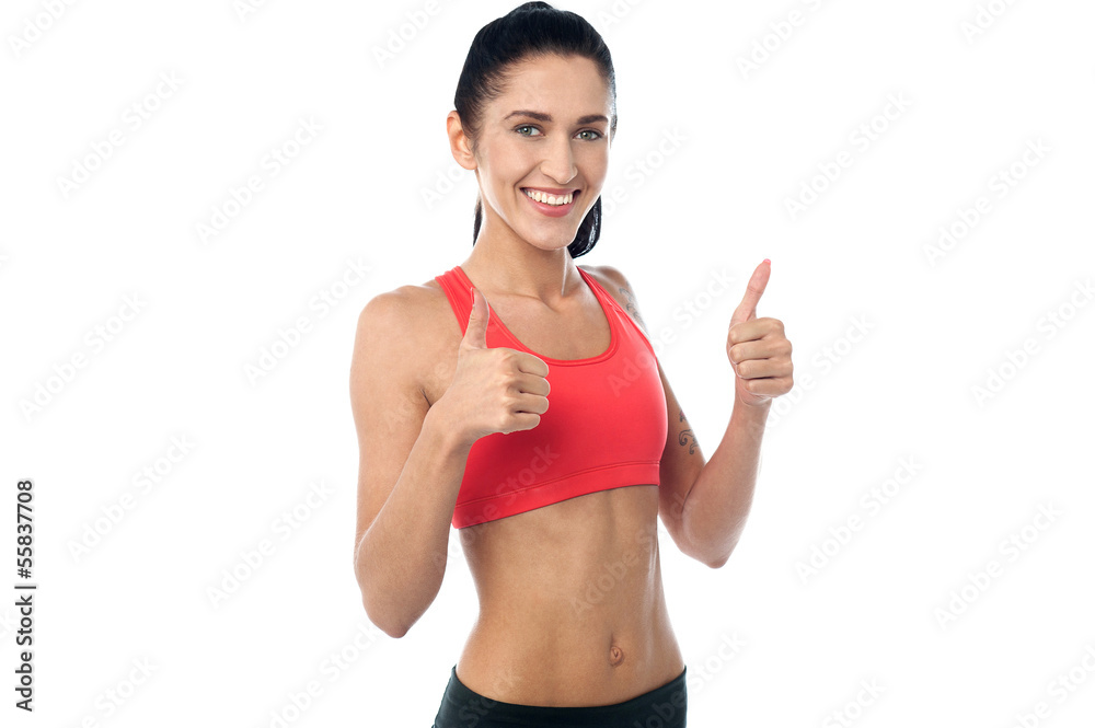 Smiling fit woman gesturing double thumbs up Smiling fit woman gesturing double thumbs up