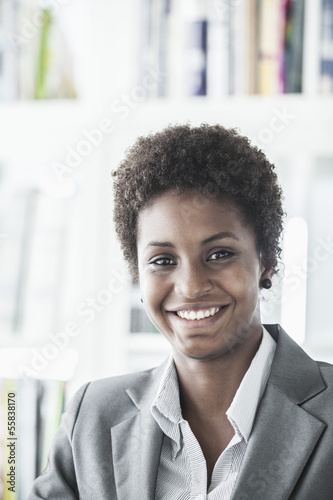 Portrait of smiling young businesswoman with short hair looking at the camera, head and shoulders