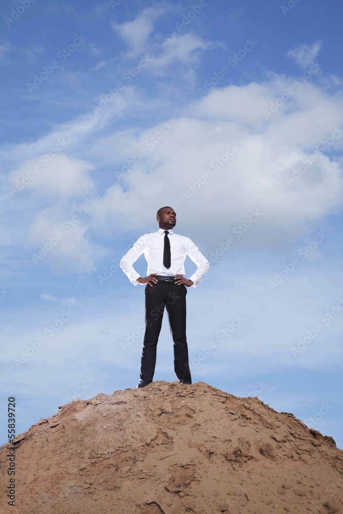 Young businessman with hands on hips in the desert