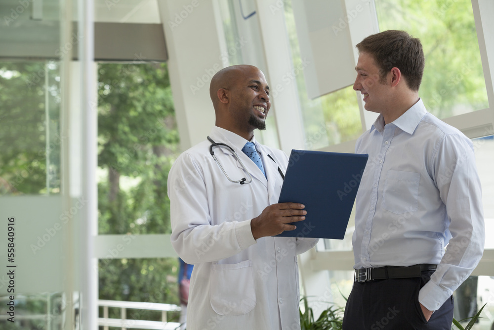Doctor and patient smiling and discussing medical record in the hospital Doctor and patient smiling and discussing medical record in the hospital
