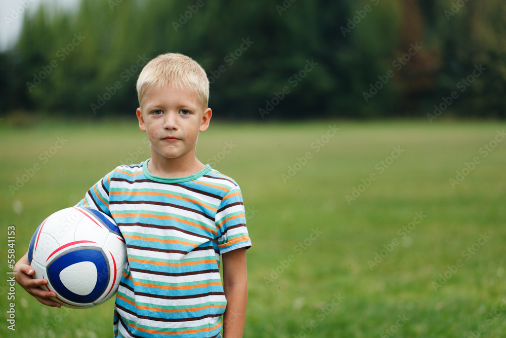 boy standing and holding ball under his arm boy standing and holding ball under his arm