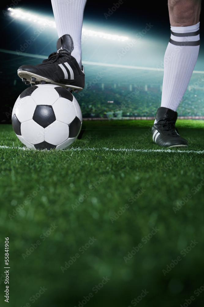 Close up of feet on top of soccer ball, night time in the stadium