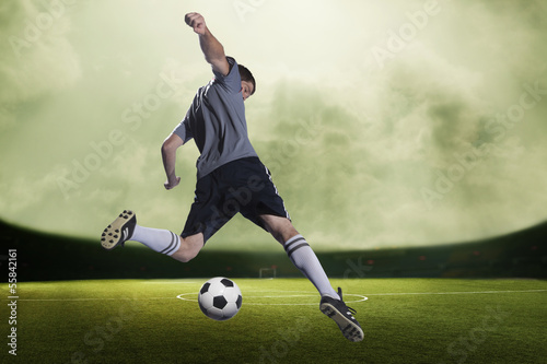 Soccer player kicking the ball in a stadium, green sky with clouds
