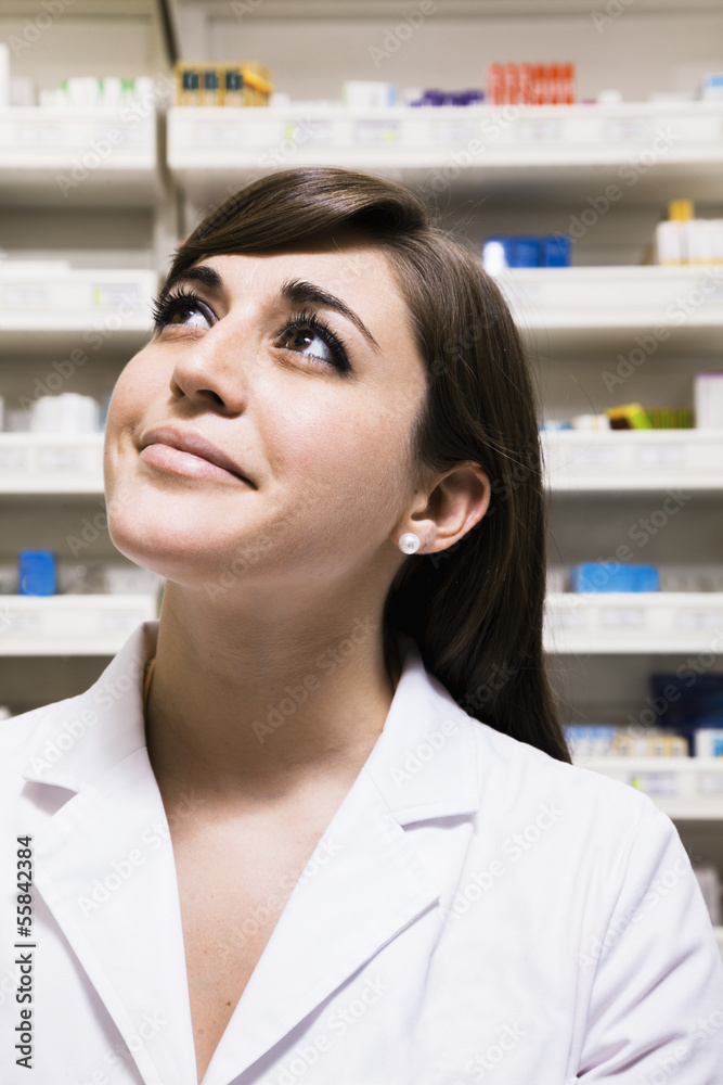Smiling pharmacist looking up in a pharmacy Smiling pharmacist looking up in a pharmacy