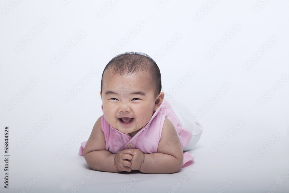 Portrait of smiling and laughing baby lying down, studio shot, white background Portrait of smiling and laughing baby lying down, studio shot, white background