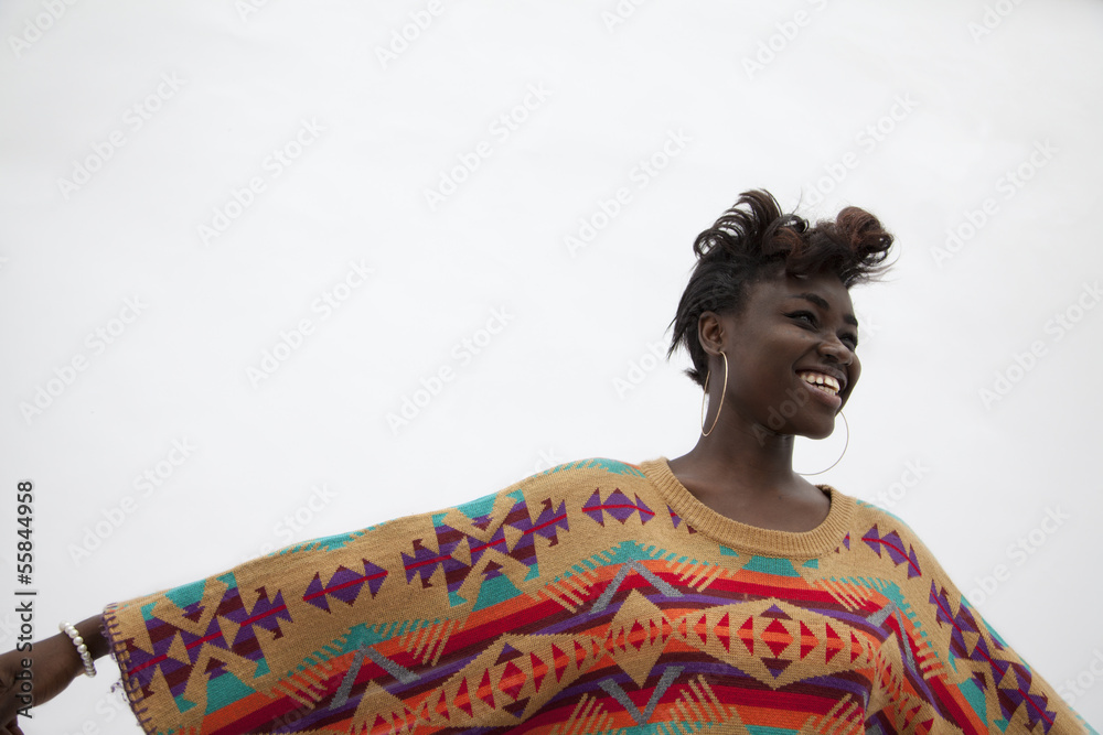 Fototapeta premium Portrait of young smiling woman holding her arms out in traditional clothing from Africa, studio shot