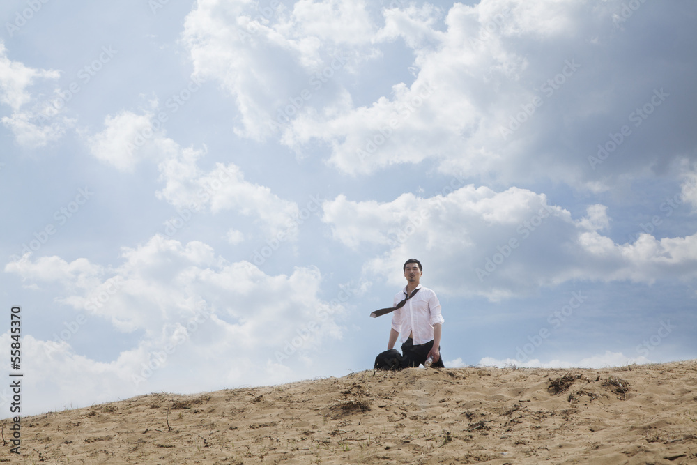 Obraz premium Young businessman lost and walking through the desert, distant 