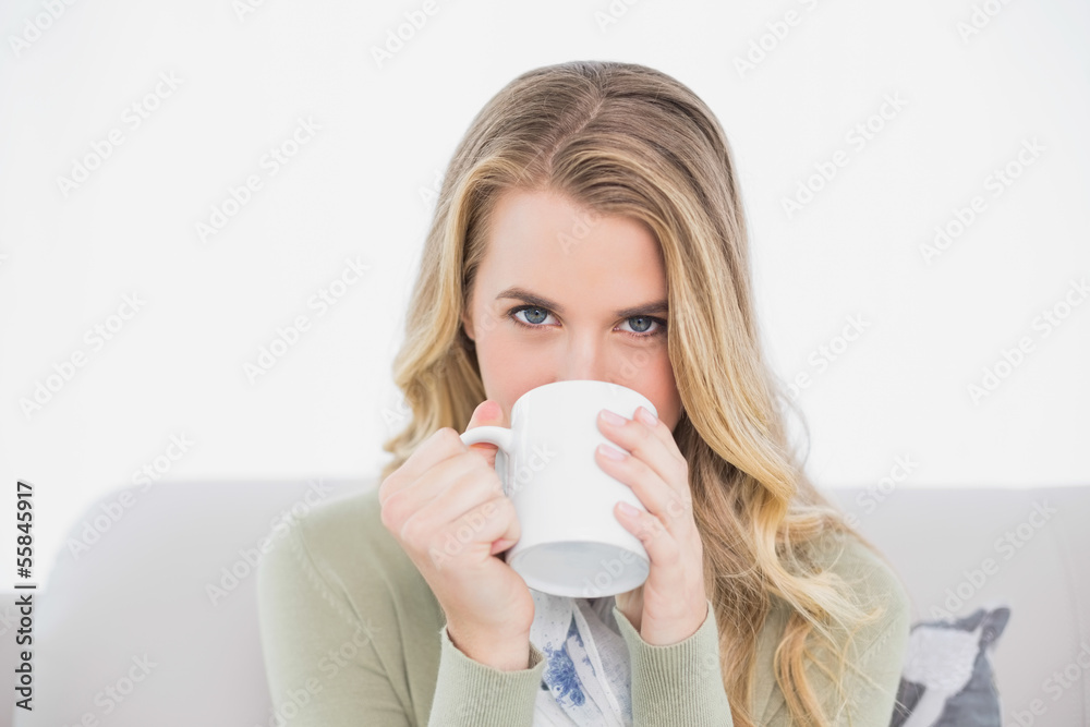 Cute blonde drinking coffee sitting on cosy sofa Cute blonde drinking coffee sitting on cosy sofa
