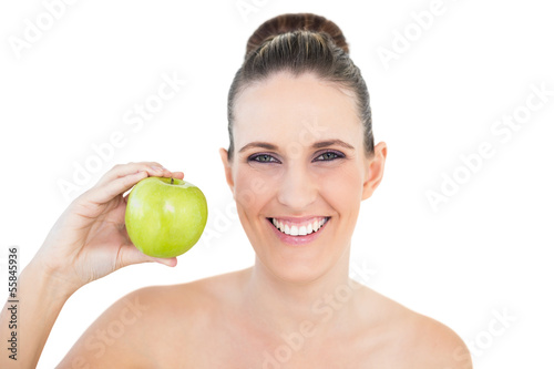 Smiling woman holding green apple looking at camera