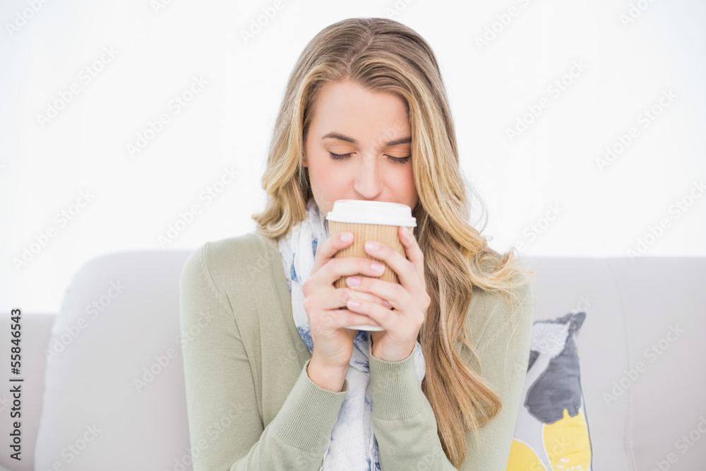 Relaxed cute blonde drinking coffee sitting on cosy sofa Relaxed cute blonde drinking coffee sitting on cosy sofa