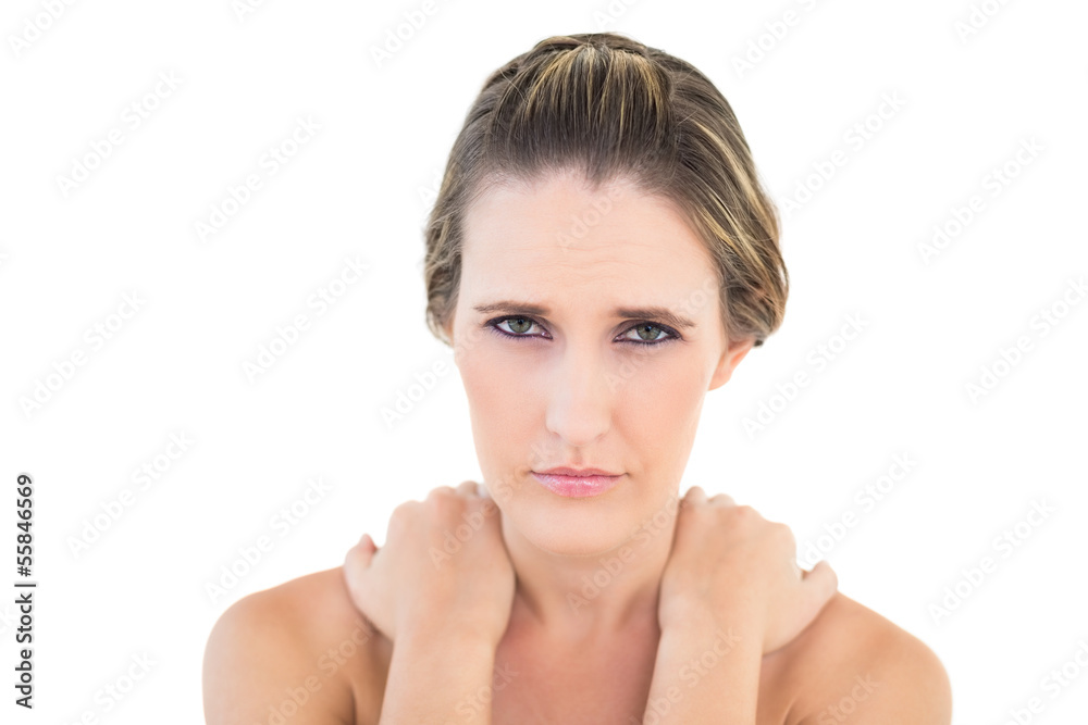 Frowning woman looking at camera with sore shoulders Frowning woman looking at camera with sore shoulders
