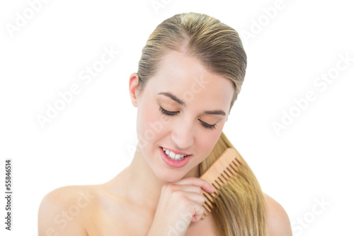 Cheerful attractive blonde combing her hair