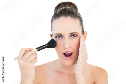 Portrait of surprised woman applying blusher