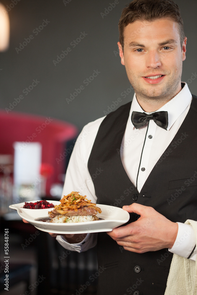 Handsome waiter serving appetizing duck dish Handsome waiter serving appetizing duck dish