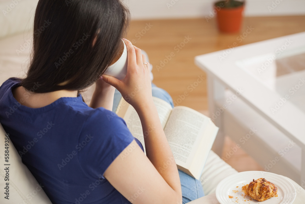 Young woman sipping her coffee and reading book Young woman sipping her coffee and reading book