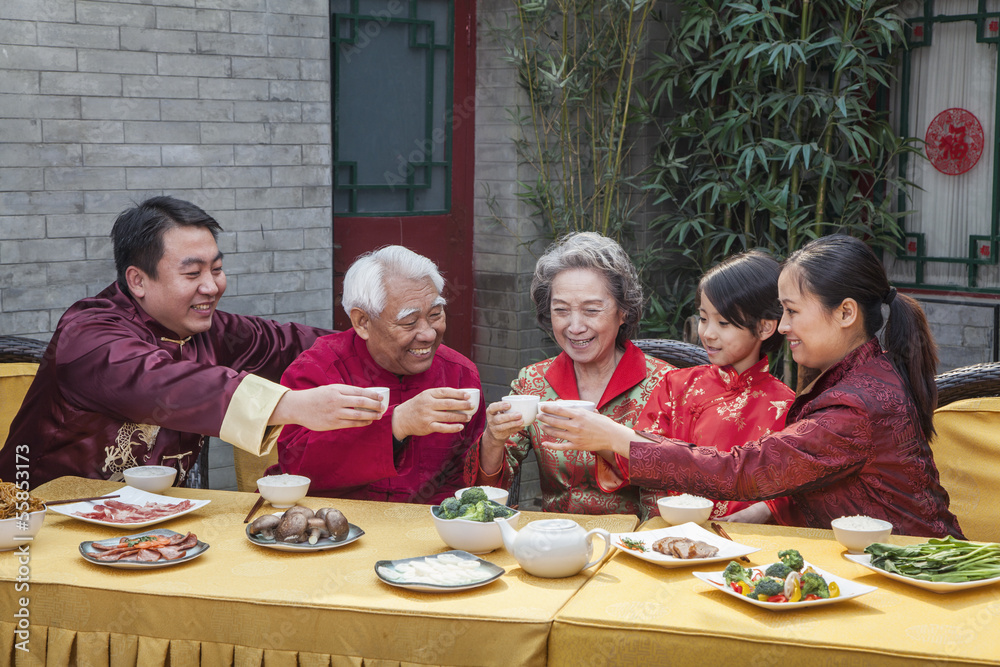 Family with cups raised toasting over a Chinese meal Family with cups raised toasting over a Chinese meal