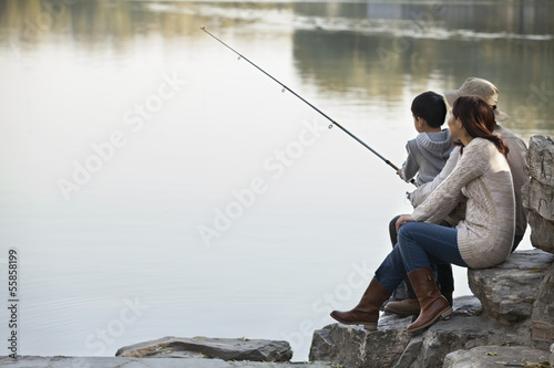 Family fishing off of rocks at lake