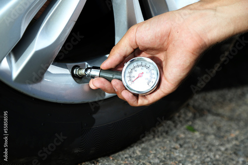 Hand holding pressure gauge for car tyre pressure measurement