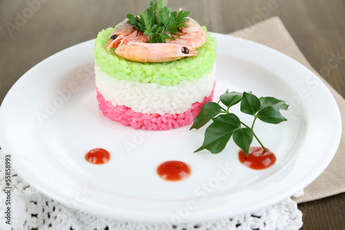 Colored rice on plate on napkin on wooden table