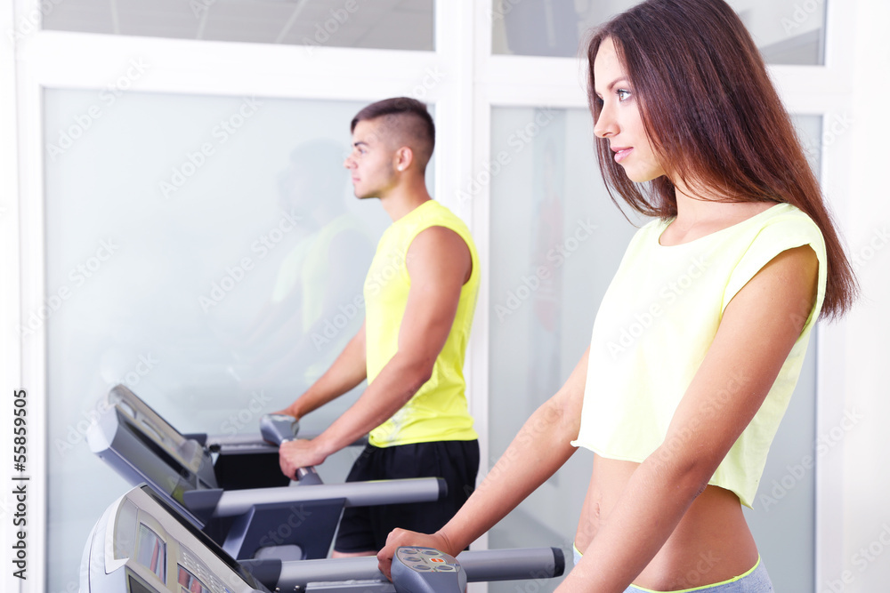 Guy and girl on treadmills at gym Guy and girl on treadmills at gym