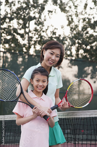 Mother and daughter playing tennis, portrait 