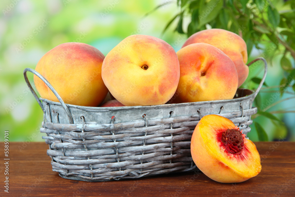 Ripe sweet peaches in wicker basket, on bright background