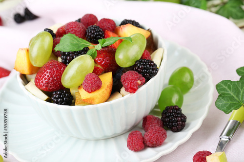 Fruit salad in bowl  on wooden table  on bright background