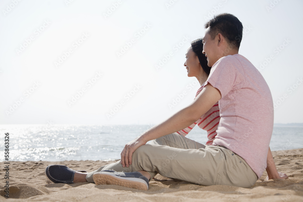Couple sitting on the beach and looking out at the ocean Couple sitting on the beach and looking out at the ocean