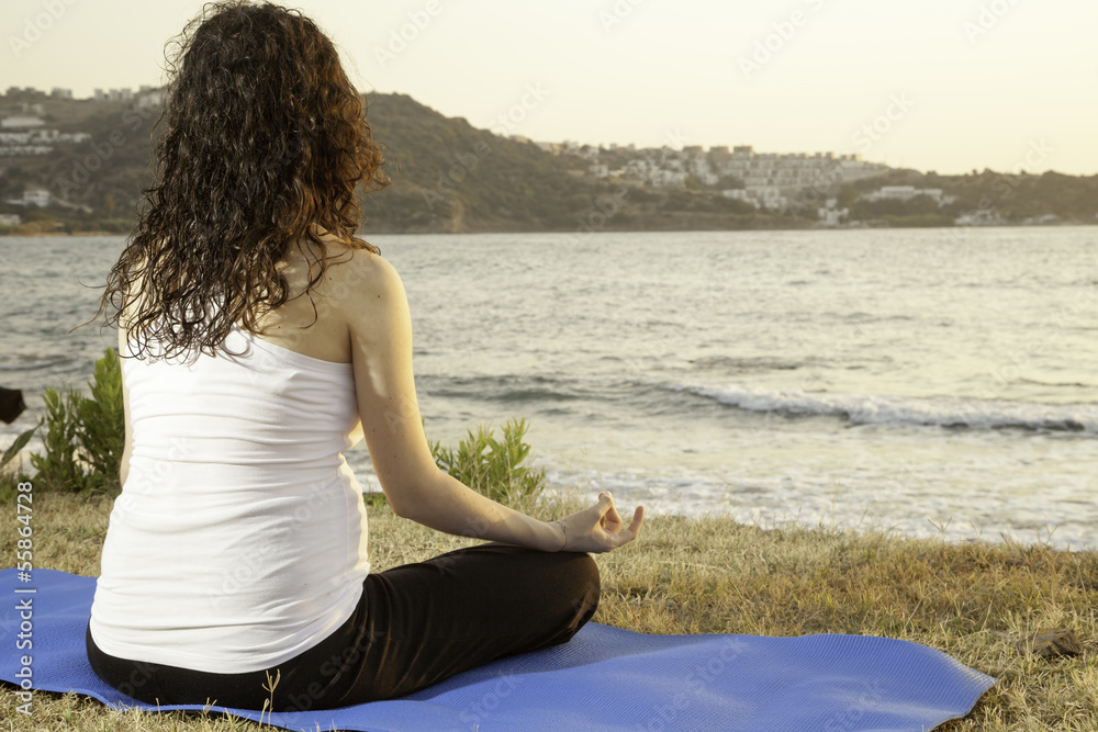 Fototapeta premium Lotus position on the seaside at sunset